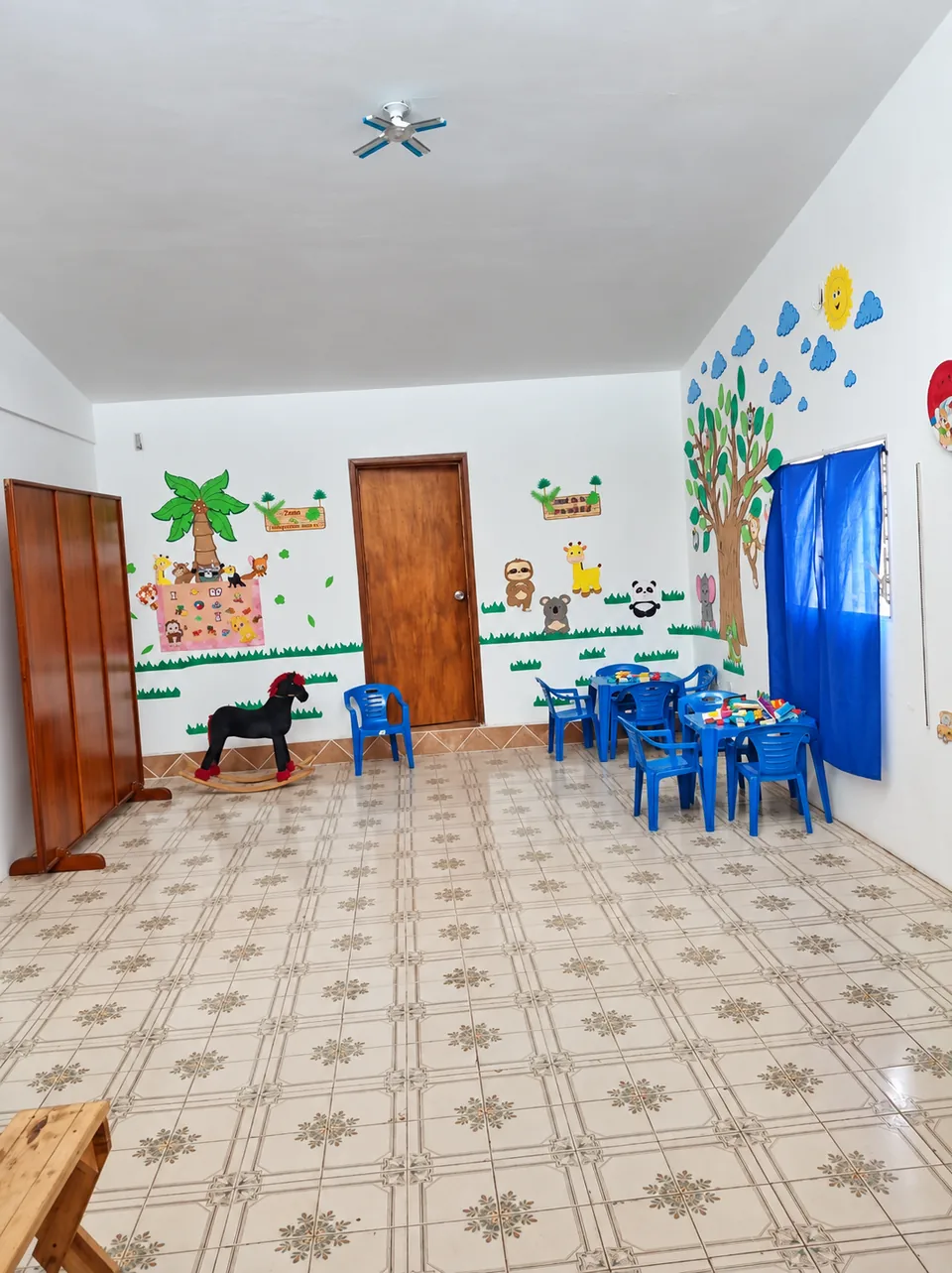 Mesas y sillas infantiles, juguetes y murales en una sala de Conectando Sentidos.